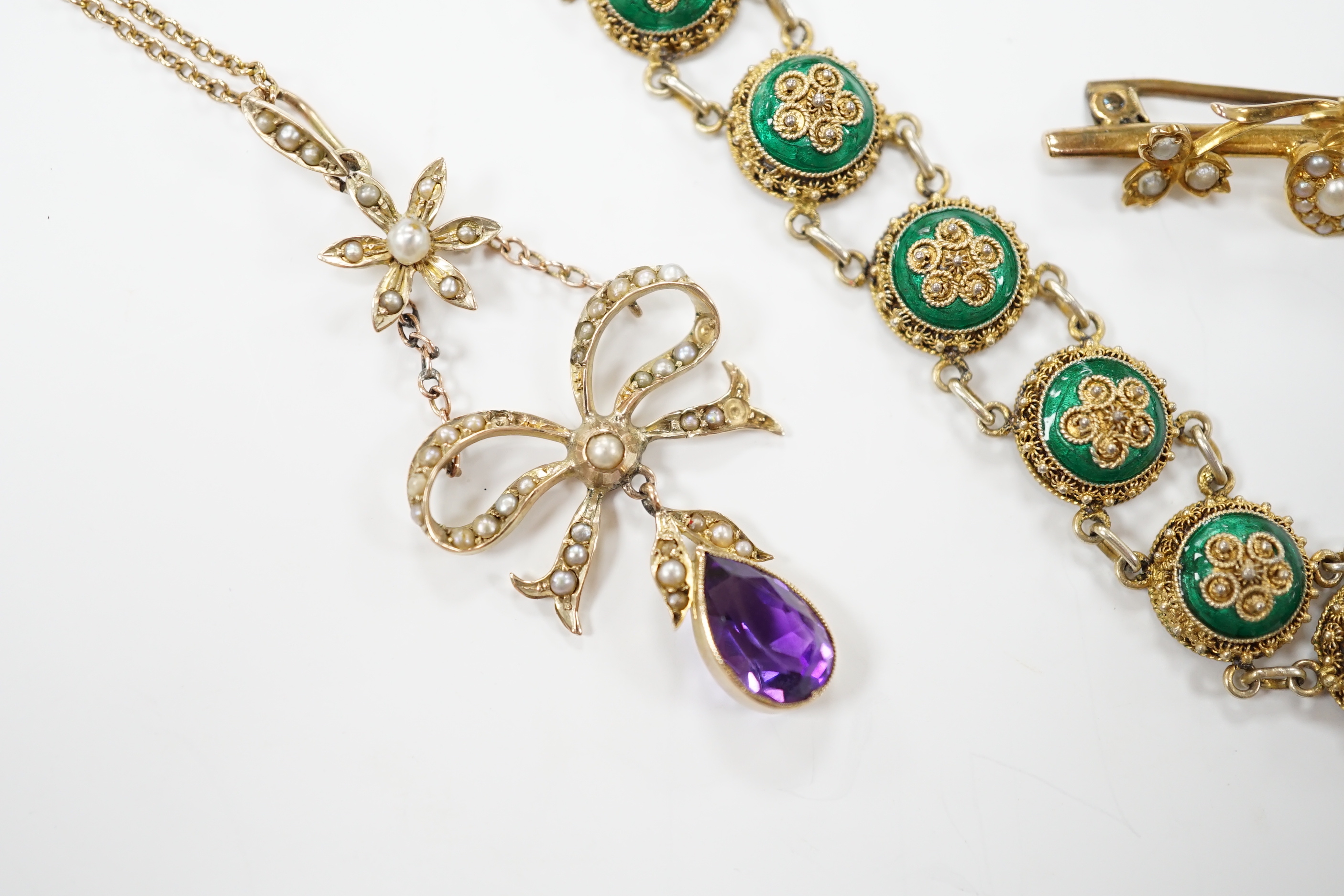 An Edwardian yellow metal, amethyst and split pearl set drop pendant, 52mm, on a yellow metal fine link chain, 45cm, a similar yellow metal and seed pearl set twin hearts bar brooch, a yellow metal and three stone ruby s
